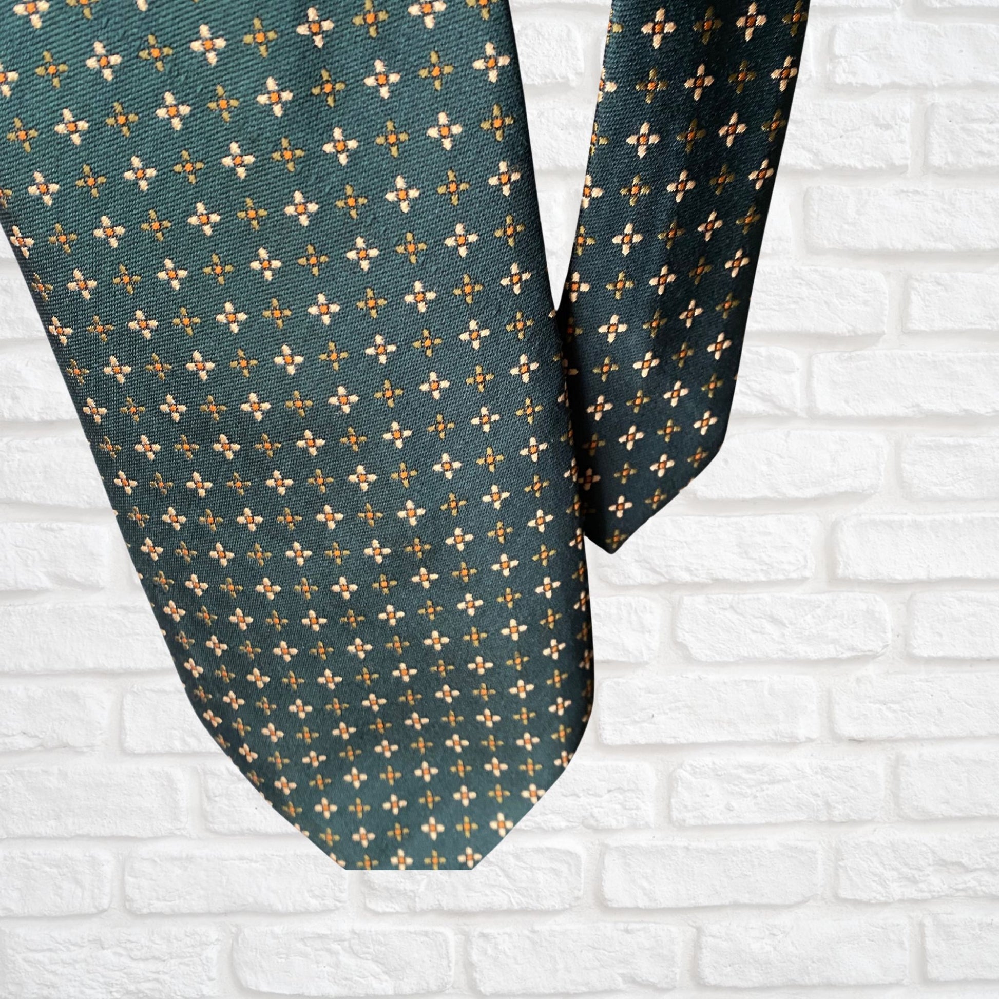 Close up of a green, orange and white geometric floral  print vintage 70s tie