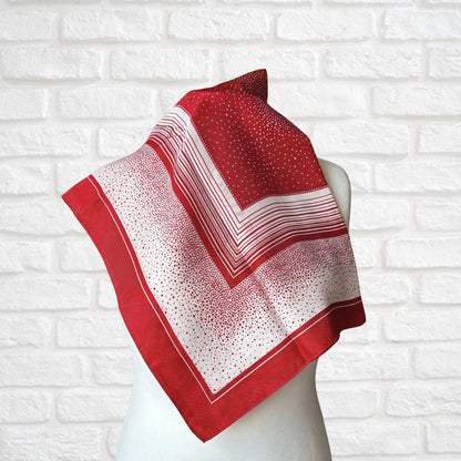 Red and white patterned scarf on a mannequin against a white brick wall background