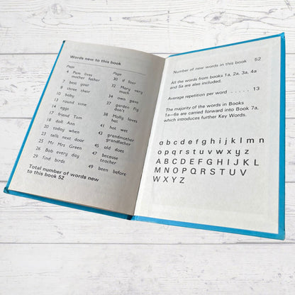 Open book with text and alphabet on a white wooden surface