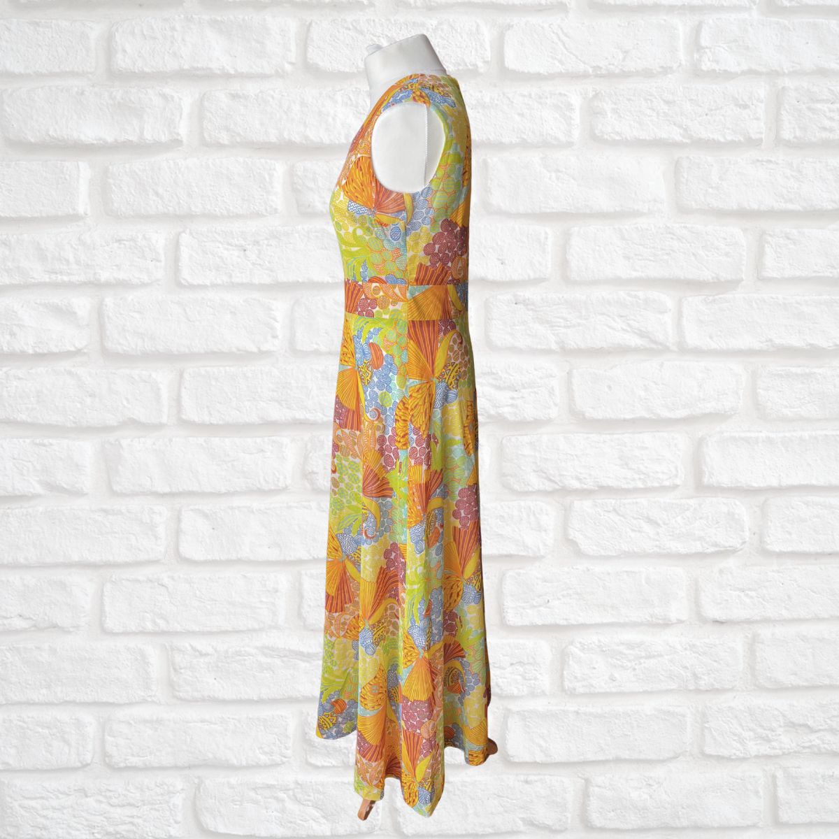 Colorful floral dress on a mannequin against a white brick wall background