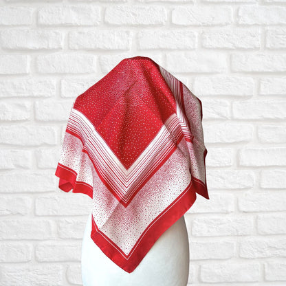 Red and white patterned scarf on a mannequin against a white brick wall background