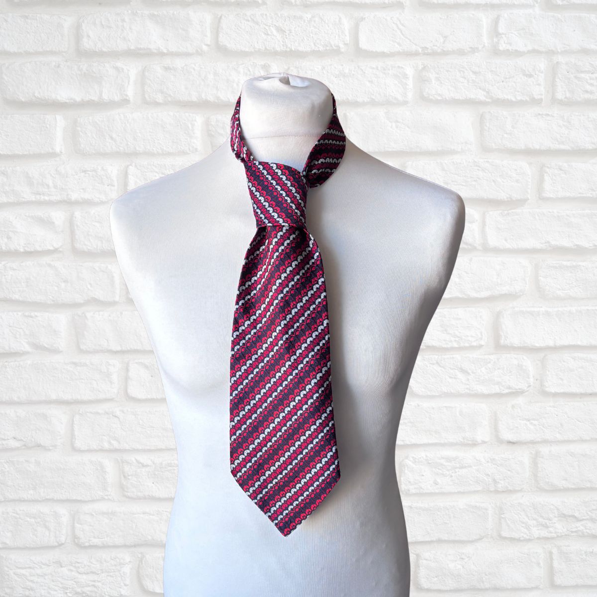 Striped necktie on a mannequin against a white brick wall background