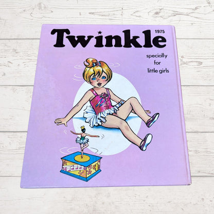 A vintage 1975 children's book titled 'Twinkle' for little girls, featuring a lavender cover with an illustration of a ballerina and a music box, placed on a light wood background.