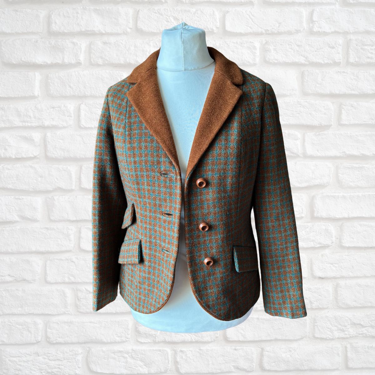 Checked blazer shown open  on a mannequin against a white brick wall background