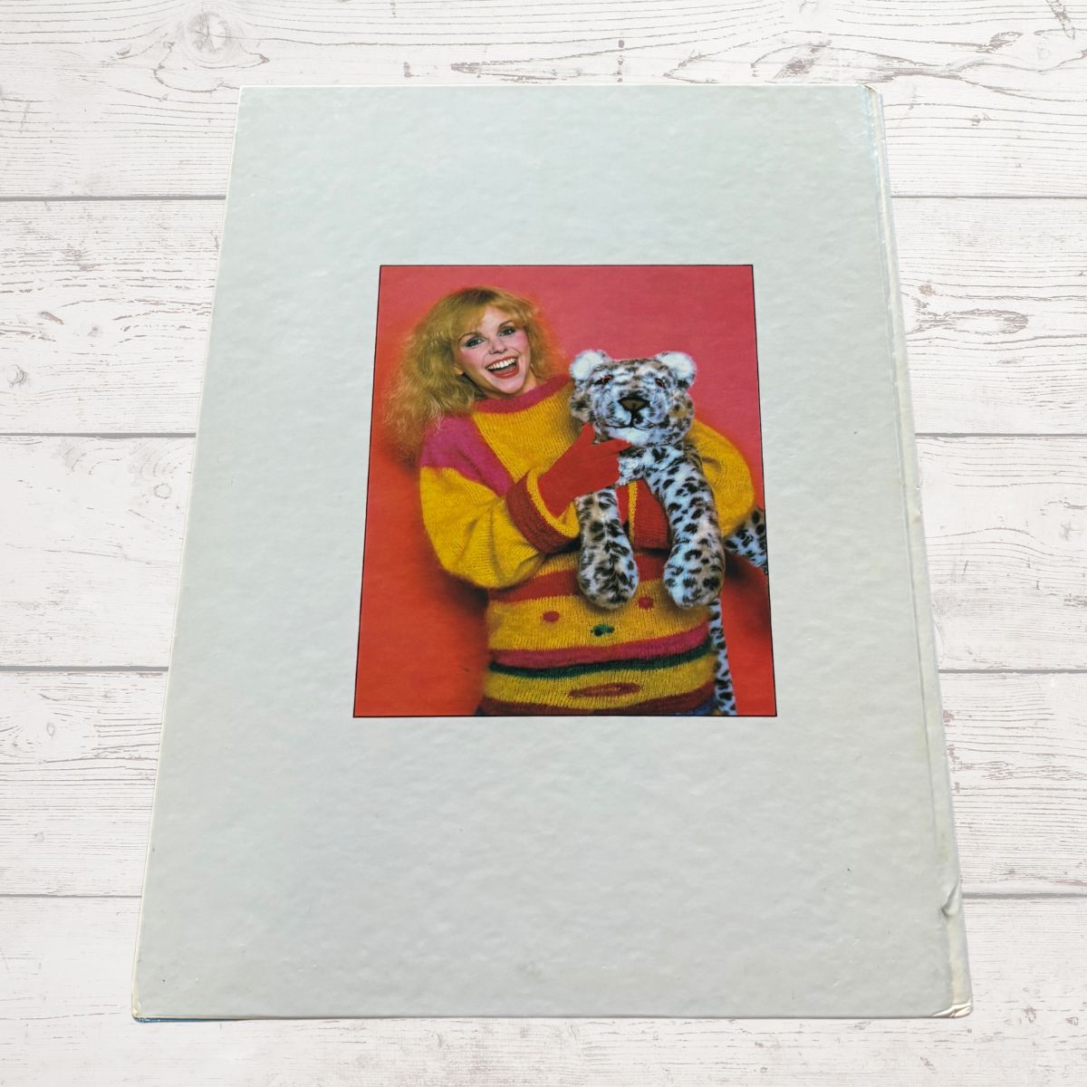 Book with a printed image of a person holding a stuffed animal on a wooden surface.