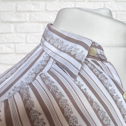 A close-up of a striped and floral-patterned button-up shirt displayed on a white mannequin torso against a white brick wall background.