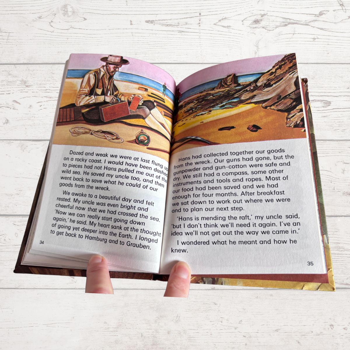 An open children's book spread laid on a light wood surface, showing printed text, illustrations, and a small map on the pages.