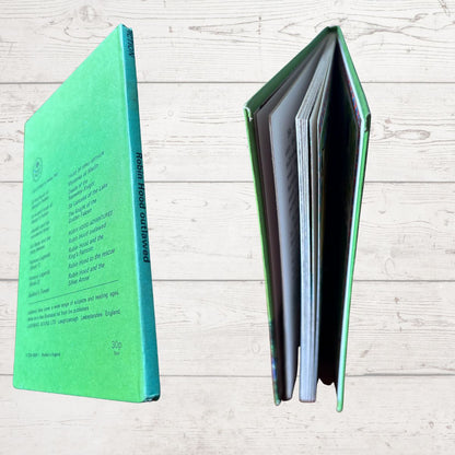 A hardcover book shown from two angles on a light wood plank background: the back cover on the left in bright green with black text, and the open middle spread on the right showing multiple interior pages.