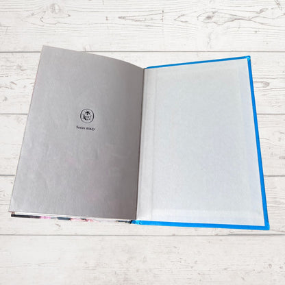 An open book lying on a white wood surface,