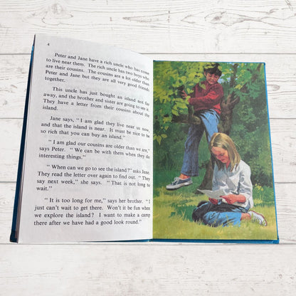 Open book with a colorful illustration of two children in a tree and text on a wooden surface.