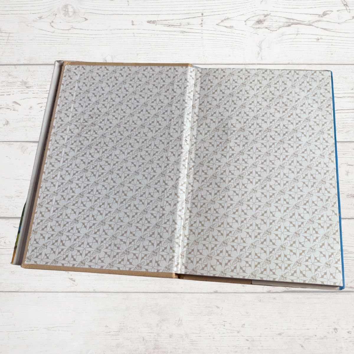 Open book  with gray patterned pages on a light wooden surface
