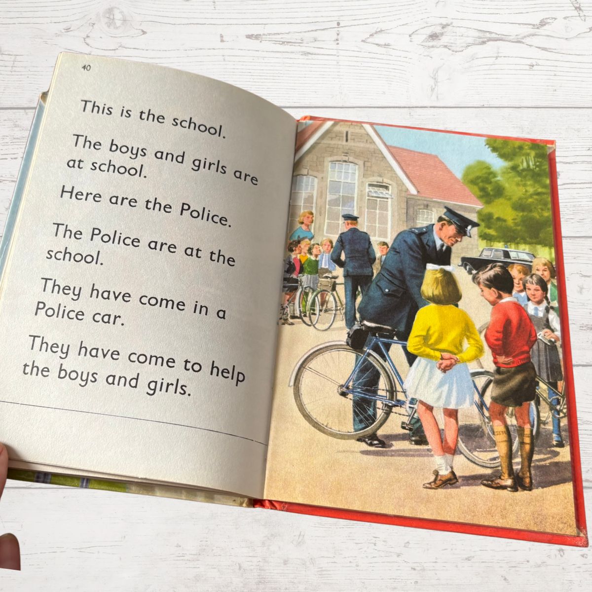 Open book with a vintage illustration of a police officer and children on a school day.