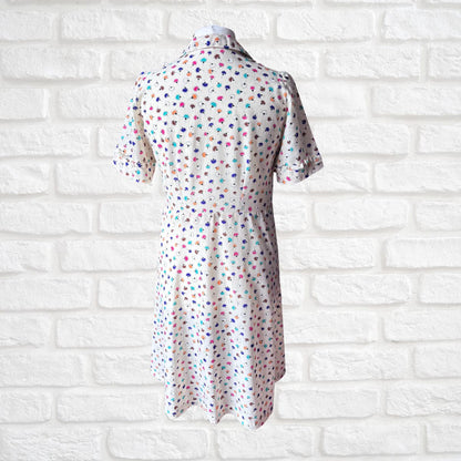 Short-sleeve dress with colorful polka dot pattern on a white brick wall background