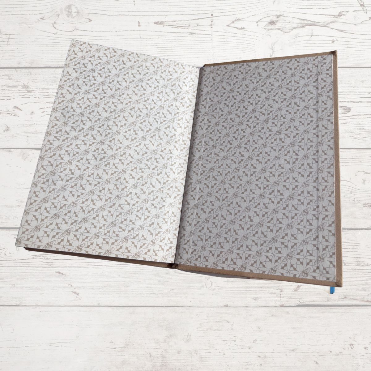 Open book  with gray patterned pages on a light wooden surface