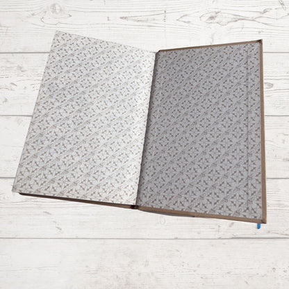 Open book  with gray patterned pages on a light wooden surface