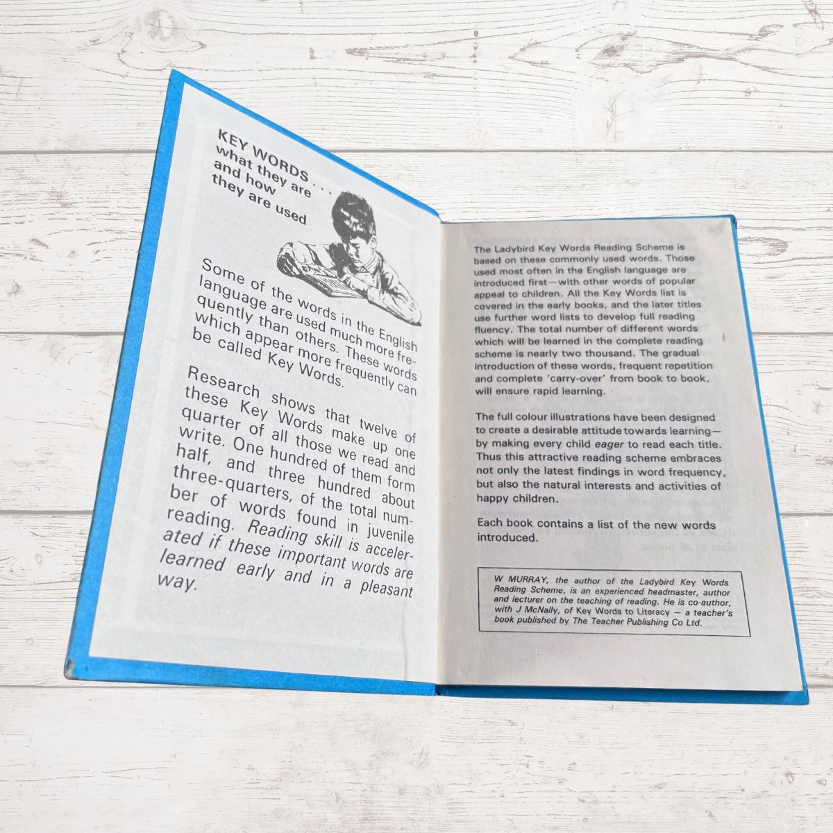 Open book with text and a black and white illustration on a wooden surface