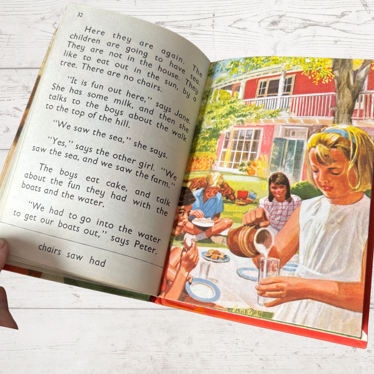 Open book with a colorful illustration of children at a picnic and text on a white wooden surface.