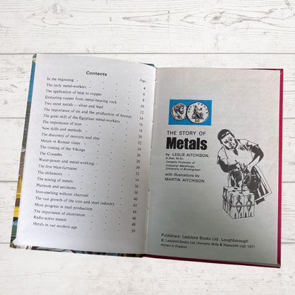 An open book showing the front and back table of contents pages, titled 'The Story of Metals' by Leslie Aitchison, photographed on a white wood surface.