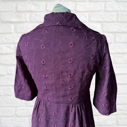 Purple dress with floral pattern on a white brick wall background