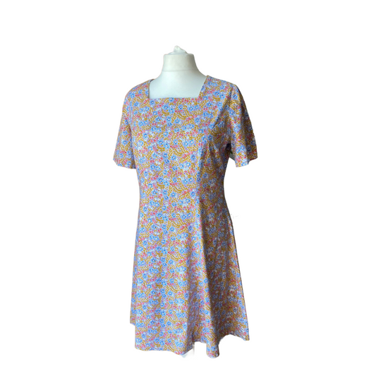 Mauve vintage dress with dark yellow leave sprig and blue, red and white flowers. Square neckline and short sleeves. 
