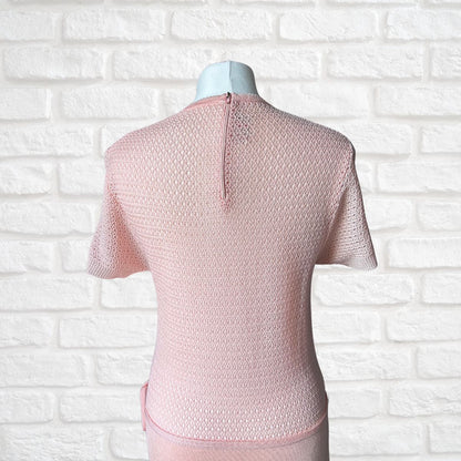 A light pink short-sleeve dress displayed on a mannequin torso, shown from the back against a white brick wall background.