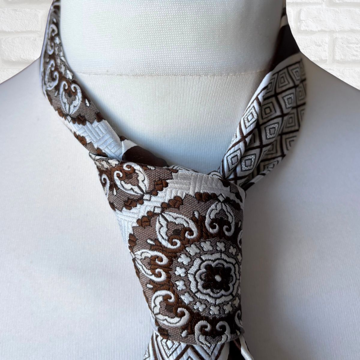 Necktie with brown and white pattern on a mannequin against a white background