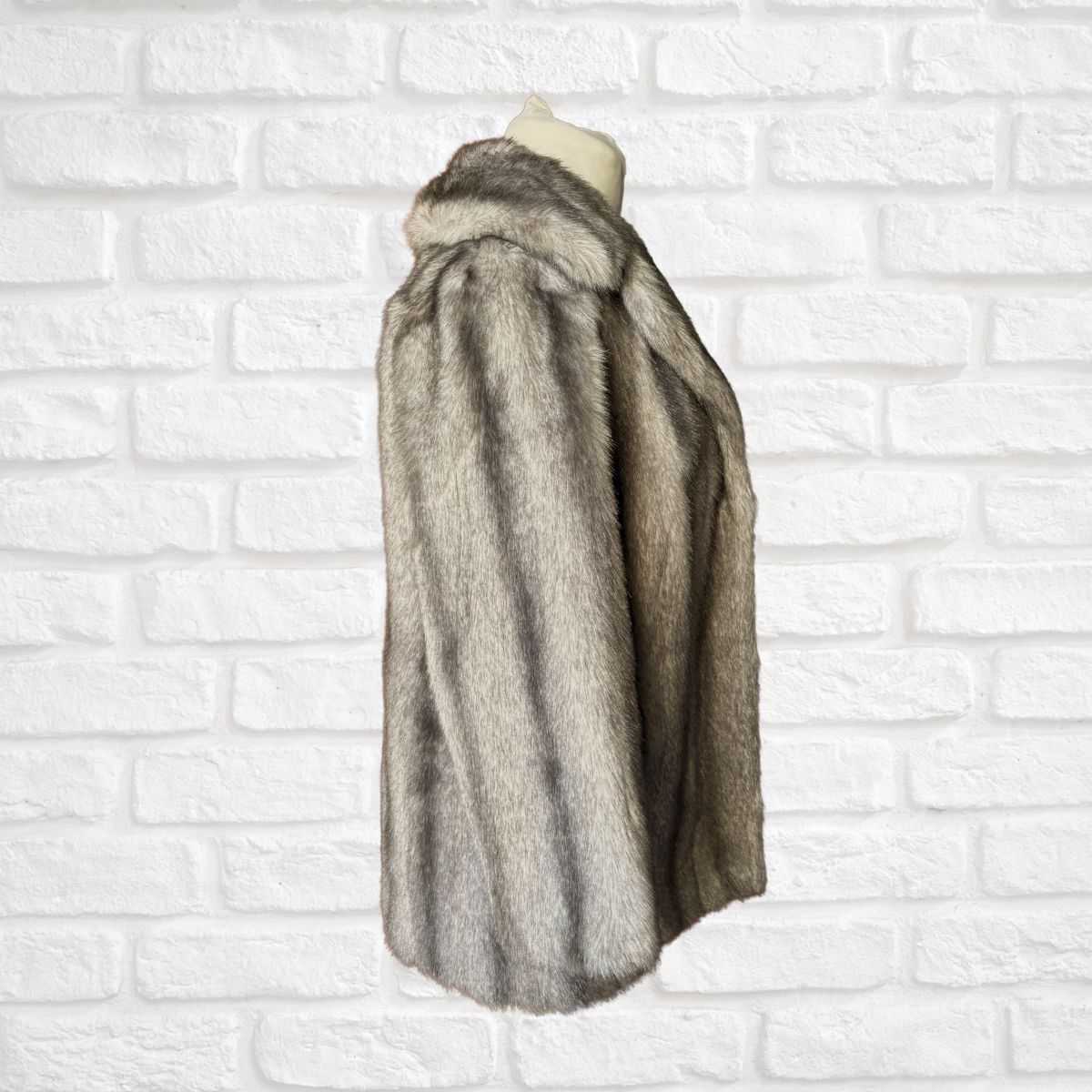 Fur coat on a mannequin against a white brick wall background