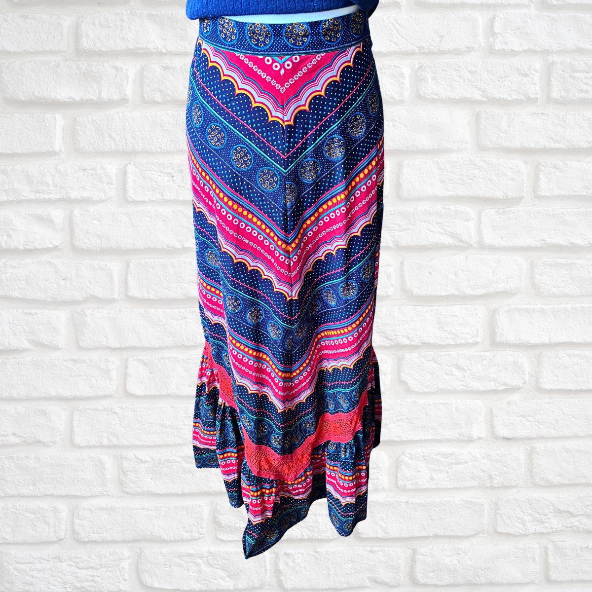 Colorful patterned skirt against a white brick wall