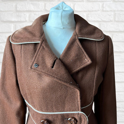 Brown coat on a mannequin against a white brick wall background
