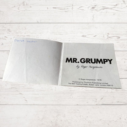 Open book with 'MR. GRUMPY' title on a light wooden surface
