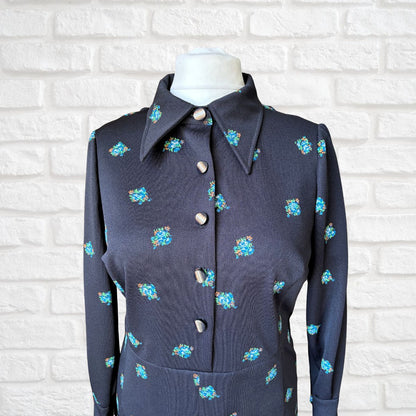 Black dress with floral patterns on a white brick wall background