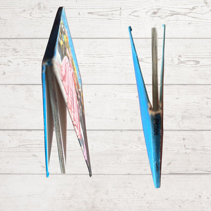 A blue  book shown from two angles on a light whitewashed wood plank background.