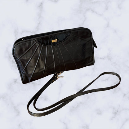 Black leather clutch bag with a strap on a light gray background