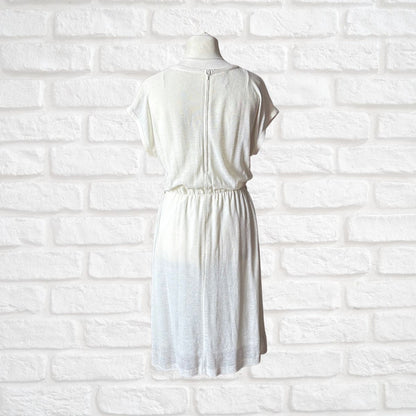Cream dress on a mannequin against a white brick wall