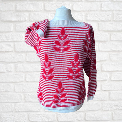 A red and white striped knit sweater with red floral motifs, displayed on a white mannequin torso against a white brick wall background.