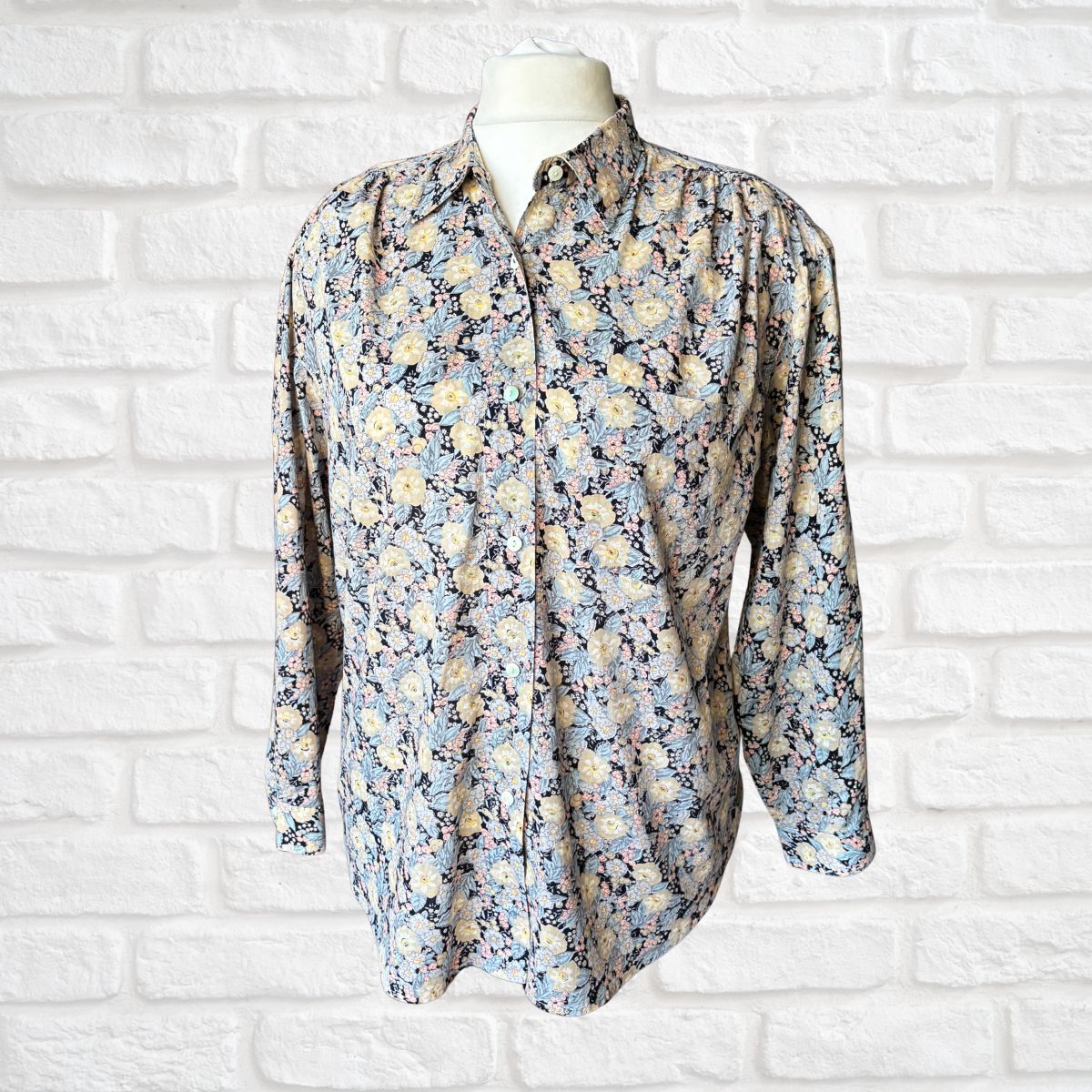 Floral patterned shirt on a mannequin against a white brick wall background