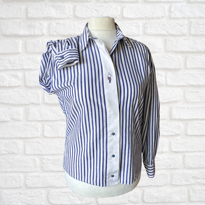 Blue and white striped shirt on a mannequin against a white brick wall background