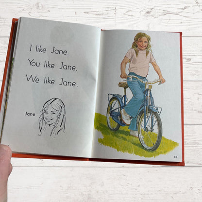 Open book with illustrations of a girl on a bike and text about 'Jane'.