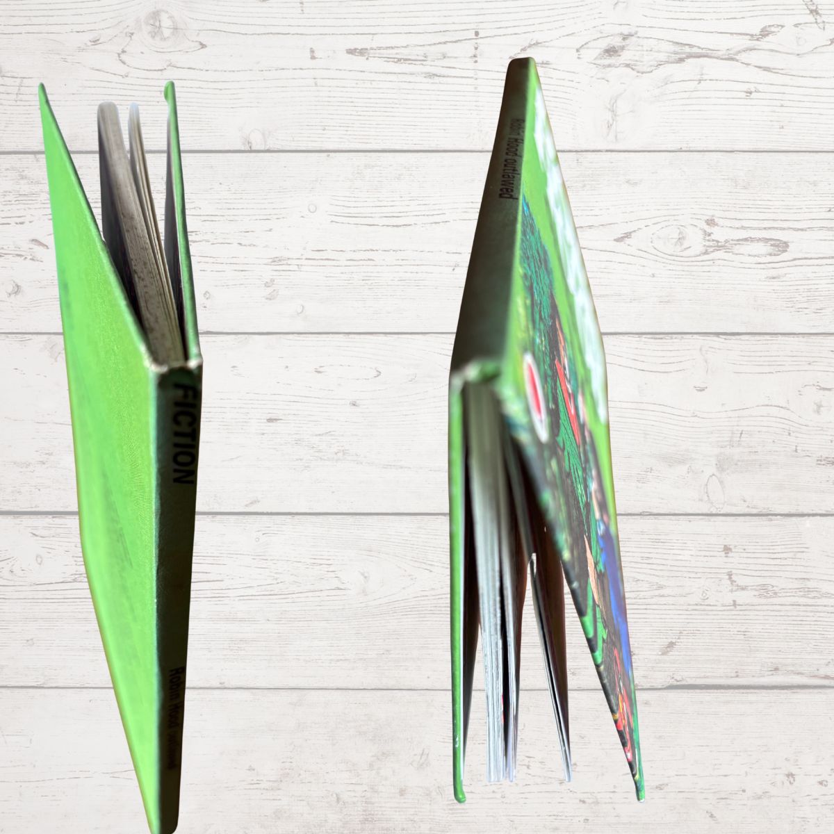 A bright green book standing open in two views against a light wood plank background, showing the colorful illustrated cover 