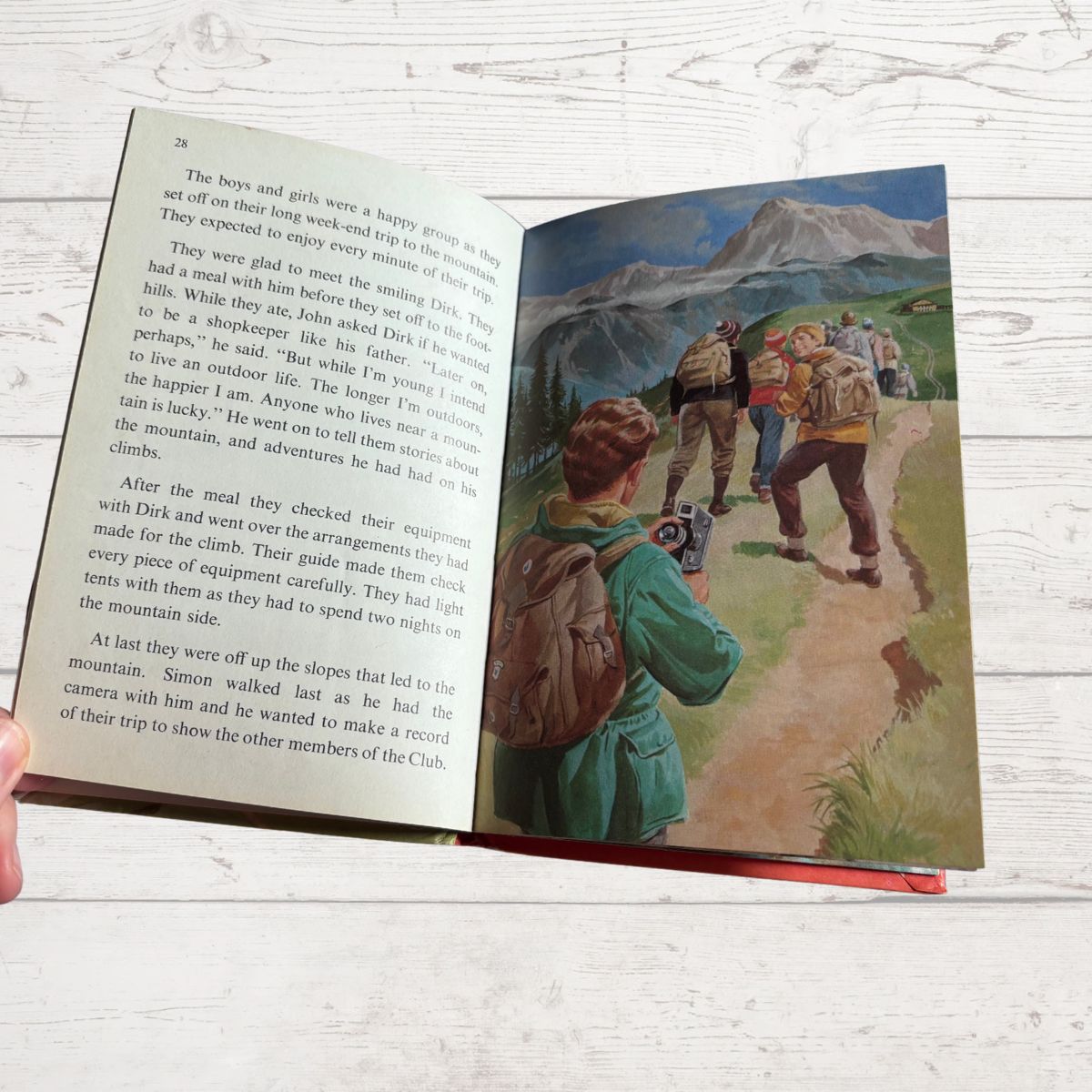 Open book with a illustration of children hiking on a mountain path