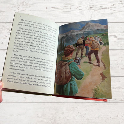 Open book with a illustration of children hiking on a mountain path