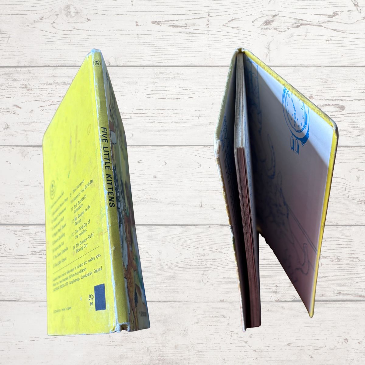 A children's book titled 'Five Little Kittens' shown standing open and closed on a light wood plank background. The cover is bright yellow, with the title printed vertically on the spine and illustrated pages visible inside.