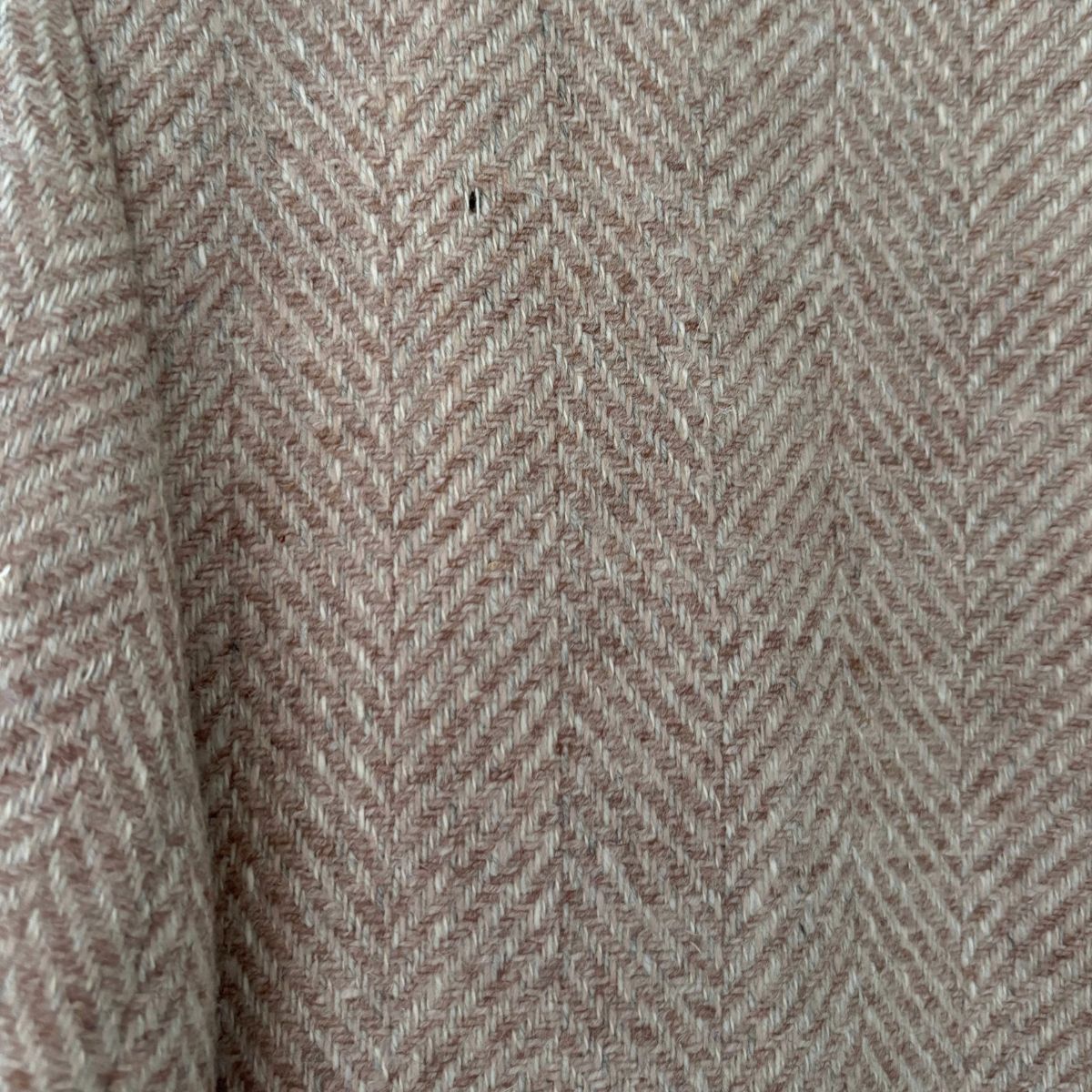 Close-up of a herringbone jacket in a warm taupe-beige color with subtle brown undertones.