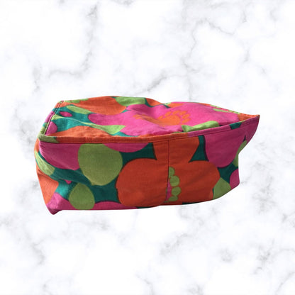 A bag with a bold retro floral pattern in pink, orange, green, and dark teal, set against a white marble background