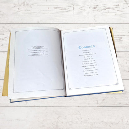 An open book showing the Table of Contents on the right page, photographed from above on a light whitewashed wood surface.