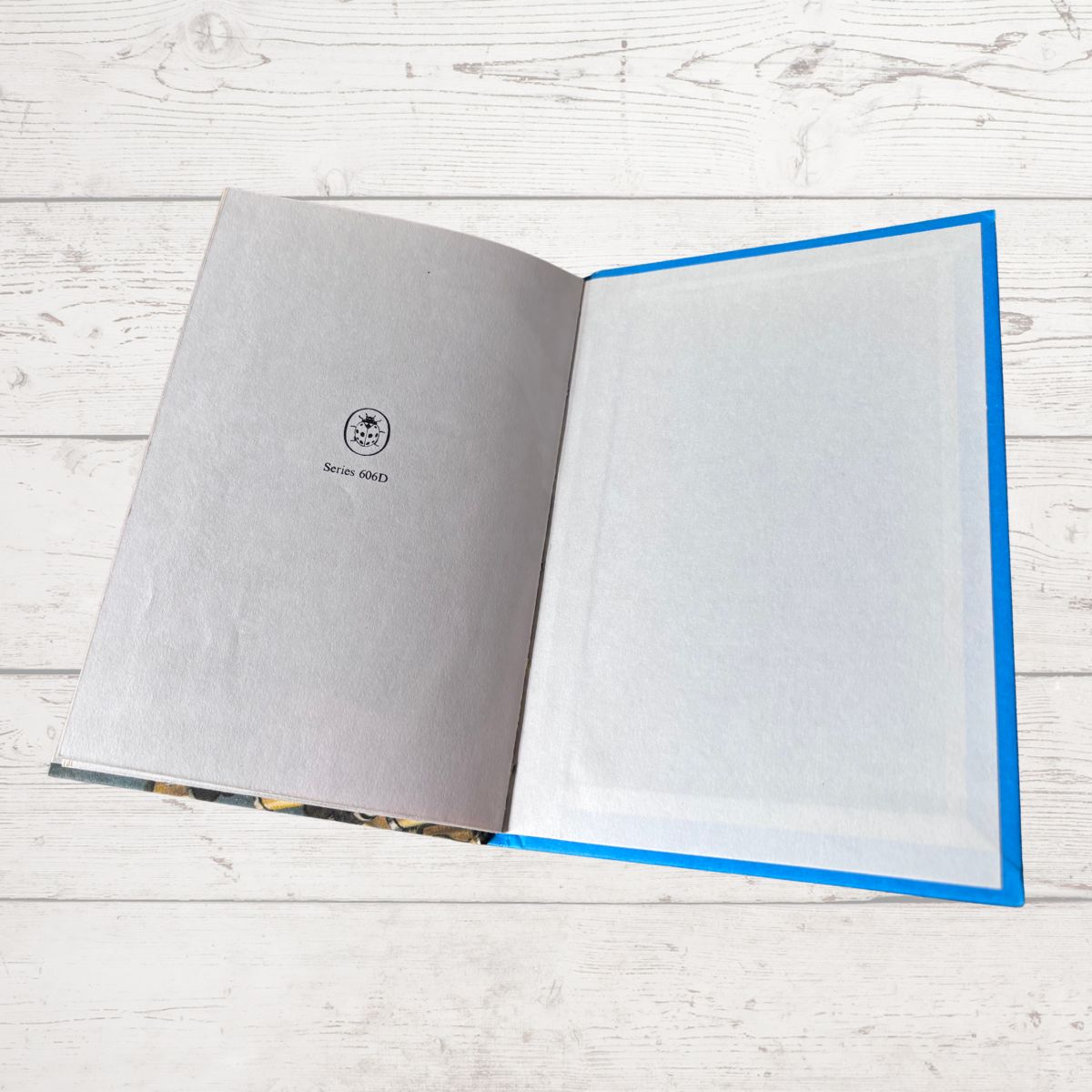 An open book on lying on a white wood plank surface. 
