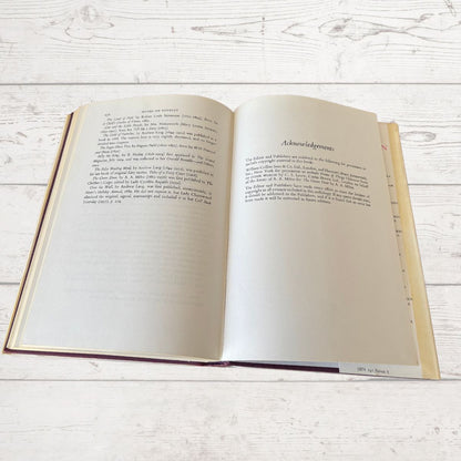 An open book with printed text on both pages, resting on a white-painted wooden surface. The right page has a heading reading 'Acknowledgements'.