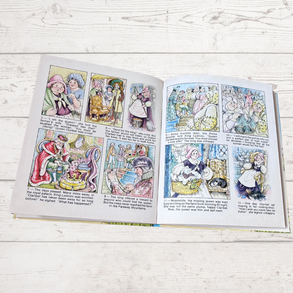An open vintage children's book with illustrated Christmas story pages, displayed flat on a white wooden surface.