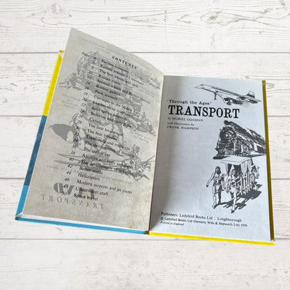 Open book with illustrations of transportation on a wooden surface