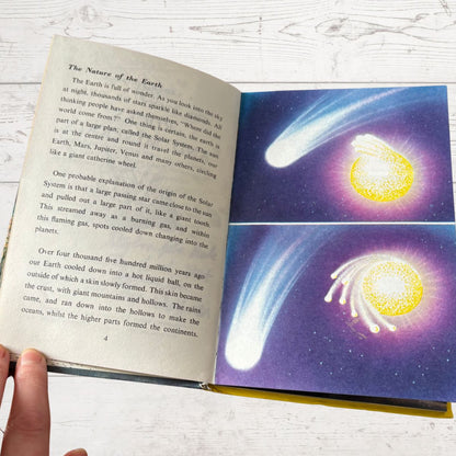 Open book with educational content on a celestial theme, featuring comets and stars.